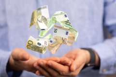 Foto: Hand mit schwebenden Geldscheinen